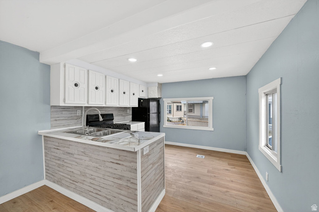 200 North Harrisville Road, Unit 37 Ogden, UT 84404 - Photo 3 of 14 Kitchen featuring light countertops, white cabinetry, tasteful backsplash, light wood-style floors, and black appliances