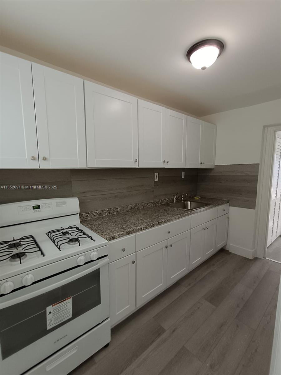 1857 Southwest 4th Street, Unit 3 Miami, FL 33135 - Photo 7 of 10 a kitchen with granite countertop white cabinets and white appliances