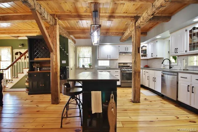 a kitchen with stainless steel appliances kitchen island granite countertop a table chairs in it and wooden floors