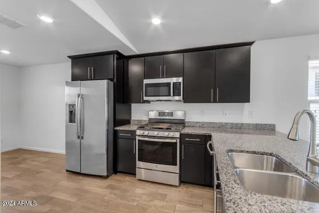 a kitchen with stainless steel appliances granite countertop a sink a stove and refrigerator