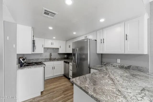 a kitchen with granite countertop a sink stove and refrigerator