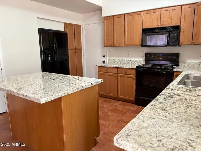a kitchen with stainless steel appliances kitchen island granite countertop a stove sink and cabinets