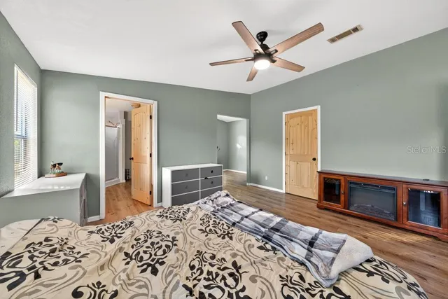 a bedroom with a bed and a dresser with wooden floor