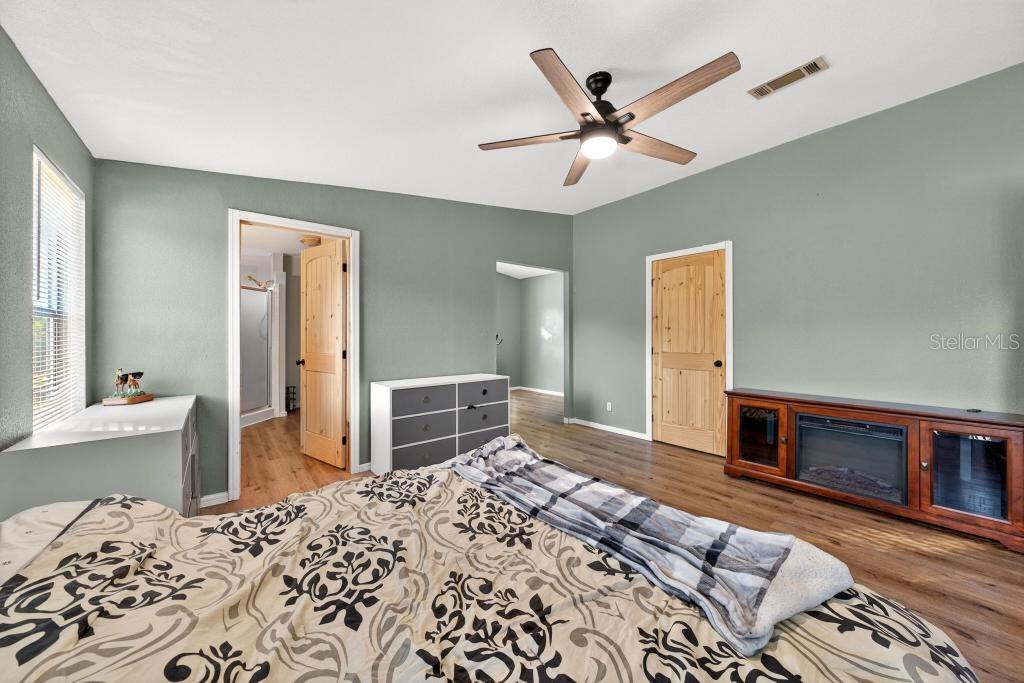 40100 Jim Scotts Road Leesburg, FL 34788 - Photo 21 of 40 a bedroom with a bed and a dresser with wooden floor