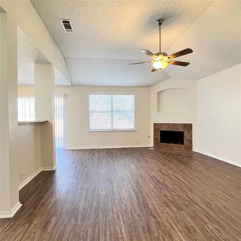 an empty room with wooden floor fan and windows