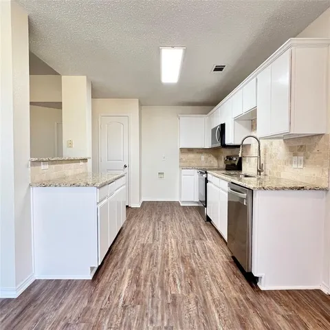 a kitchen with granite countertop a sink cabinets stainless steel appliances and a counter space