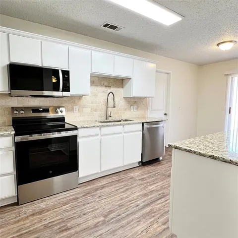 a kitchen with stainless steel appliances granite countertop a sink a stove top oven a counter space and cabinets