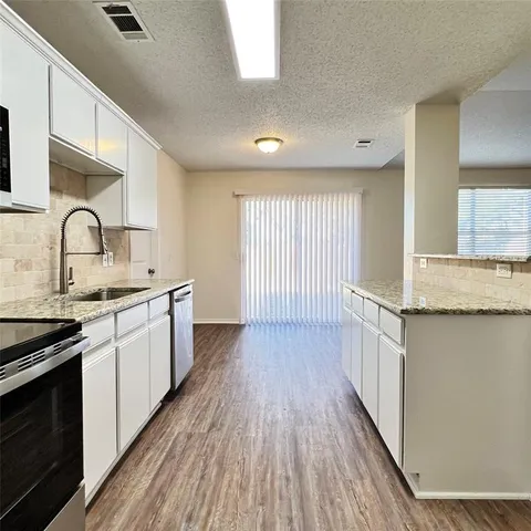 a kitchen with granite countertop wooden floors a sink and appliances