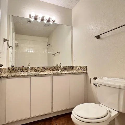 a bathroom with a granite countertop sink a toilet a mirror and vanity