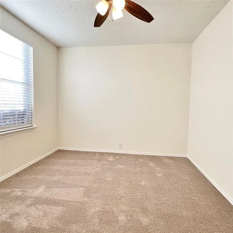 an empty room with a window and a ceiling fan