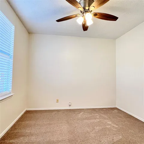 an empty room with a chandelier fan and windows