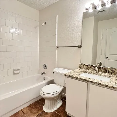 a bathroom with a granite countertop toilet sink and mirror