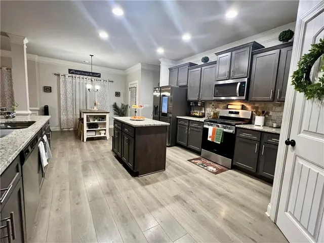 a kitchen with stainless steel appliances kitchen island granite countertop a stove refrigerator and cabinets
