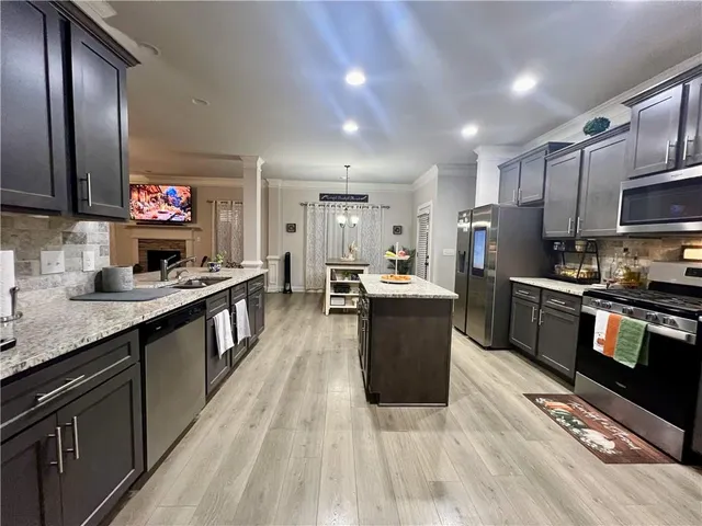 a large kitchen with stainless steel appliances and a view of living room