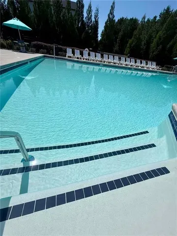 a view of a swimming pool with a table and chairs under an umbrella