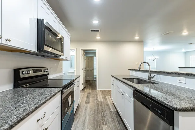 a kitchen with stainless steel appliances granite countertop a sink a stove and a microwave