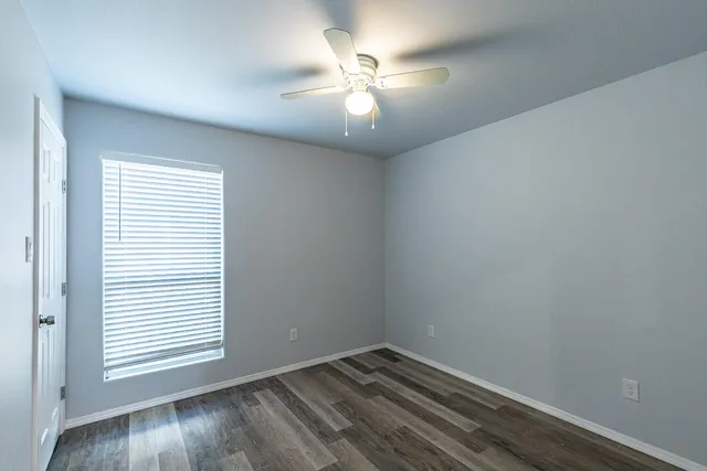 an empty room with a window and wooden floor