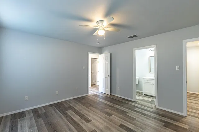 an empty room with wooden floor fan and windows