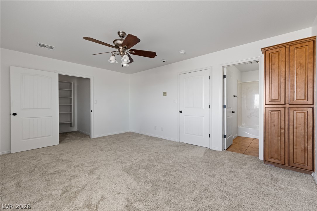 575 Gann Avenue Logandale, NV 89021 - Photo 44 of 75 A well-lit bedroom with soft carpeting and convenient closet access features a ceiling fan for comfort.