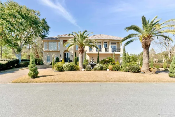 a view of a house with a yard and palm trees