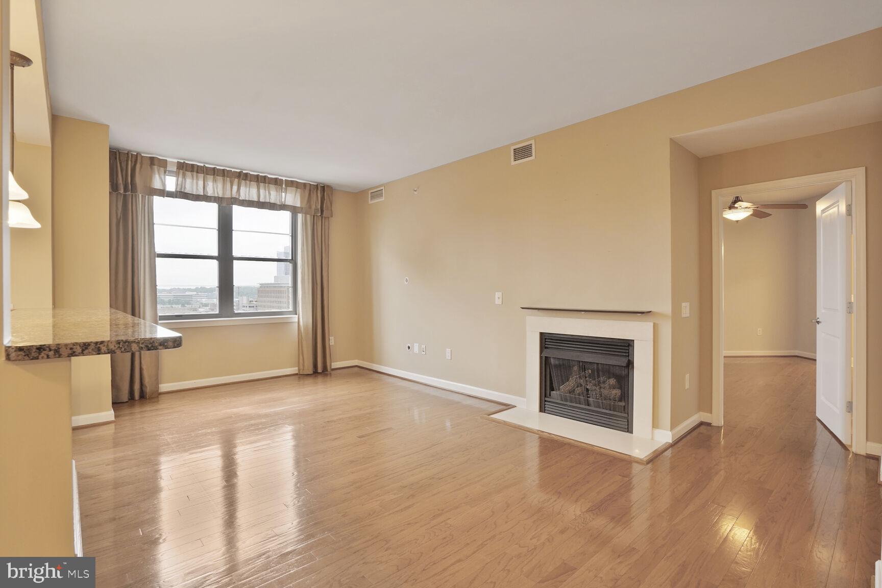 1830 Fountain Drive, Unit 1106 Reston, VA 20190 - Photo 3 of 30 an empty room with wooden floor fireplace and windows