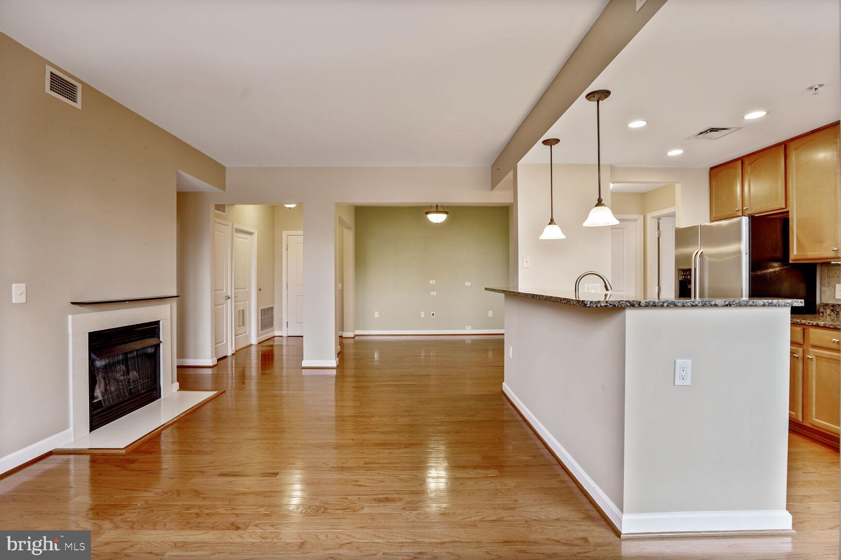 1830 Fountain Drive, Unit 1106 Reston, VA 20190 - Photo 5 of 30 a view of kitchen with kitchen island a sink wooden floor and a fireplace