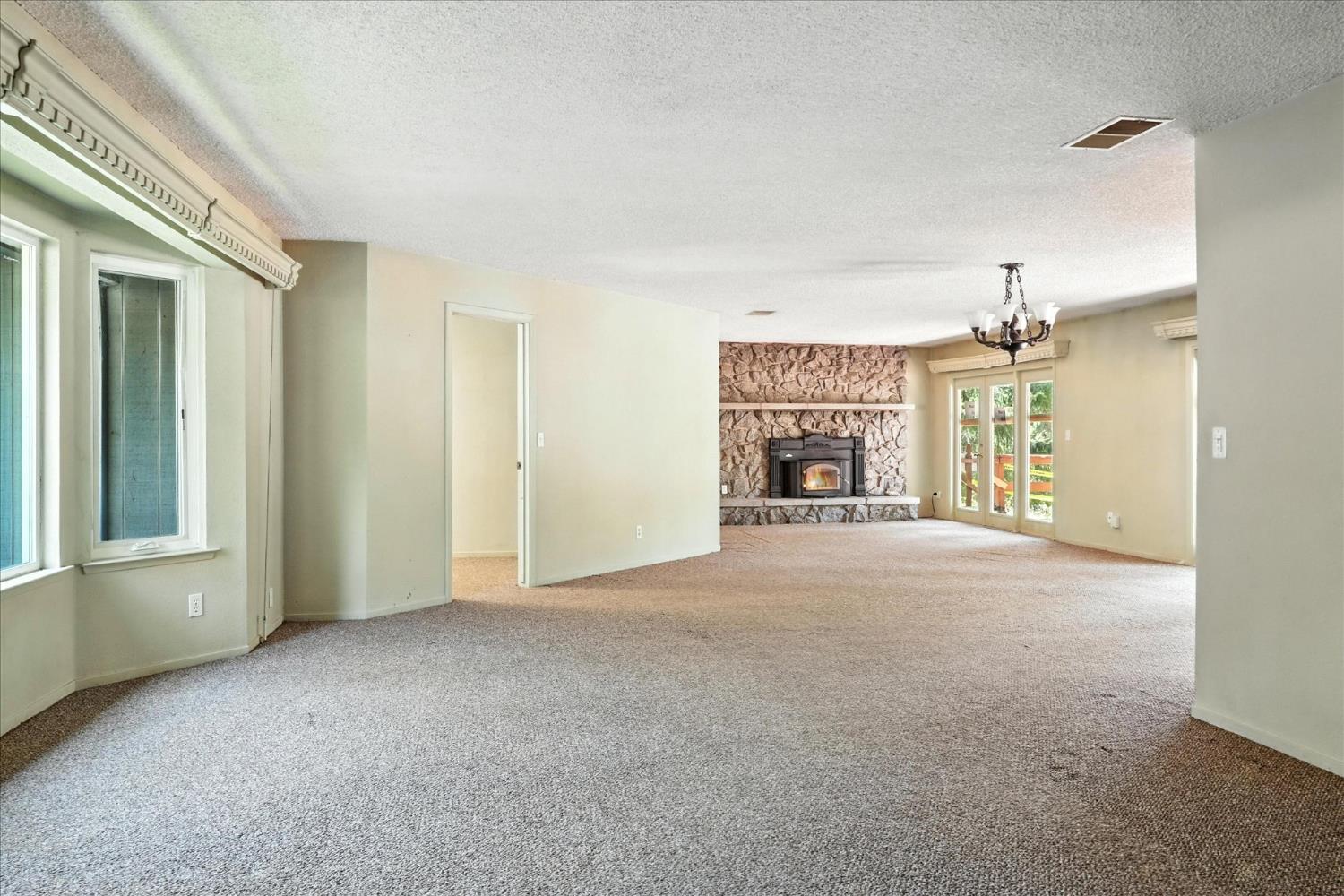 5783 Chowchilla Mountain Road Mariposa, CA 95338 - Photo 9 of 43 an empty room with fireplace and windows