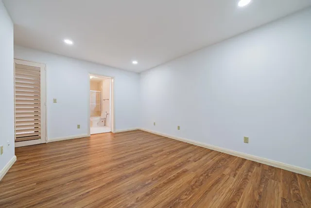 a view of an empty room with wooden floor and closet