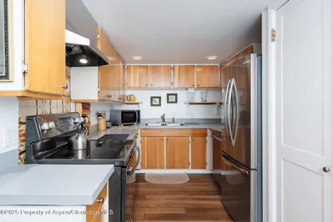a kitchen with stainless steel appliances granite countertop a refrigerator a stove a sink dishwasher and white cabinets with wooden floor