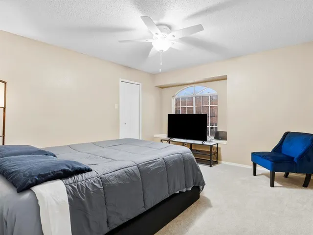 a spacious bedroom with a bed and a ceiling fan