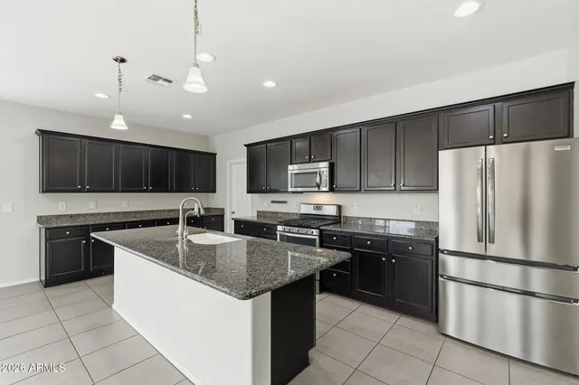 a kitchen with stainless steel appliances granite countertop a sink stove a refrigerator and a microwave