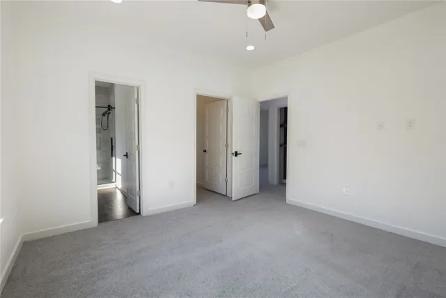 an empty room with an entryway and chandelier fan