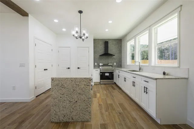 a large kitchen with granite countertop a large window and white cabinets