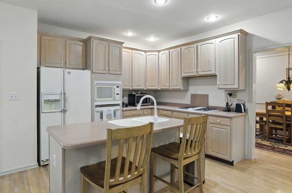 7 Alder Way, Unit 7 Bedford, MA 01730 - Photo 2 of 30 a kitchen with stainless steel appliances granite countertop a stove top oven a sink a refrigerator and white cabinets with wooden floor