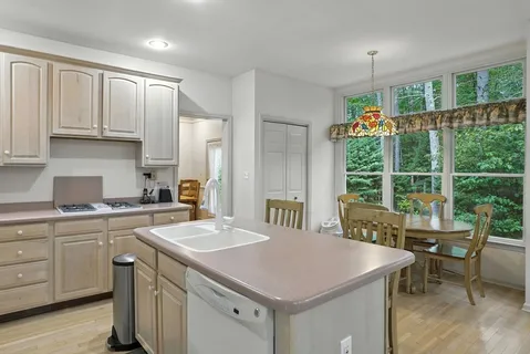 a kitchen with a stove a sink a center island and windows