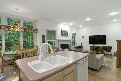 a kitchen with a sink a counter top space and living room view
