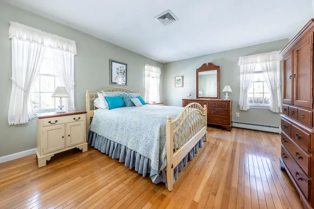 a bedroom with a bed next to a large window with wooden floor
