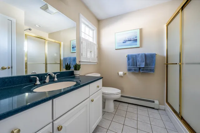 a spacious bathroom with a granite countertop sink a toilet a mirror and shower