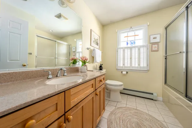 a bathroom with a granite countertop double vanity sink a mirror and a toilet