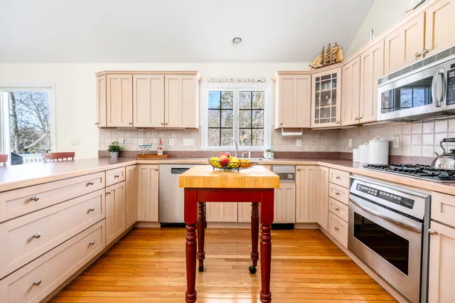 a kitchen with granite countertop a sink cabinets stainless steel appliances and a window
