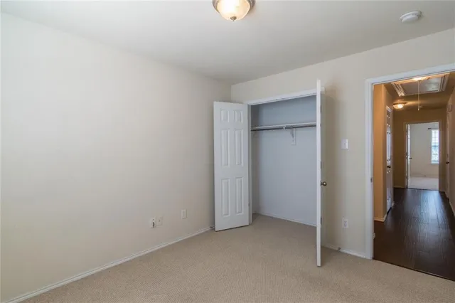 a view of an empty room with closet and a window