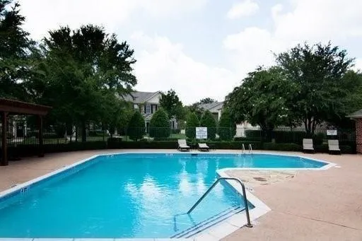 a view of a swimming pool with lawn chairs under an umbrella