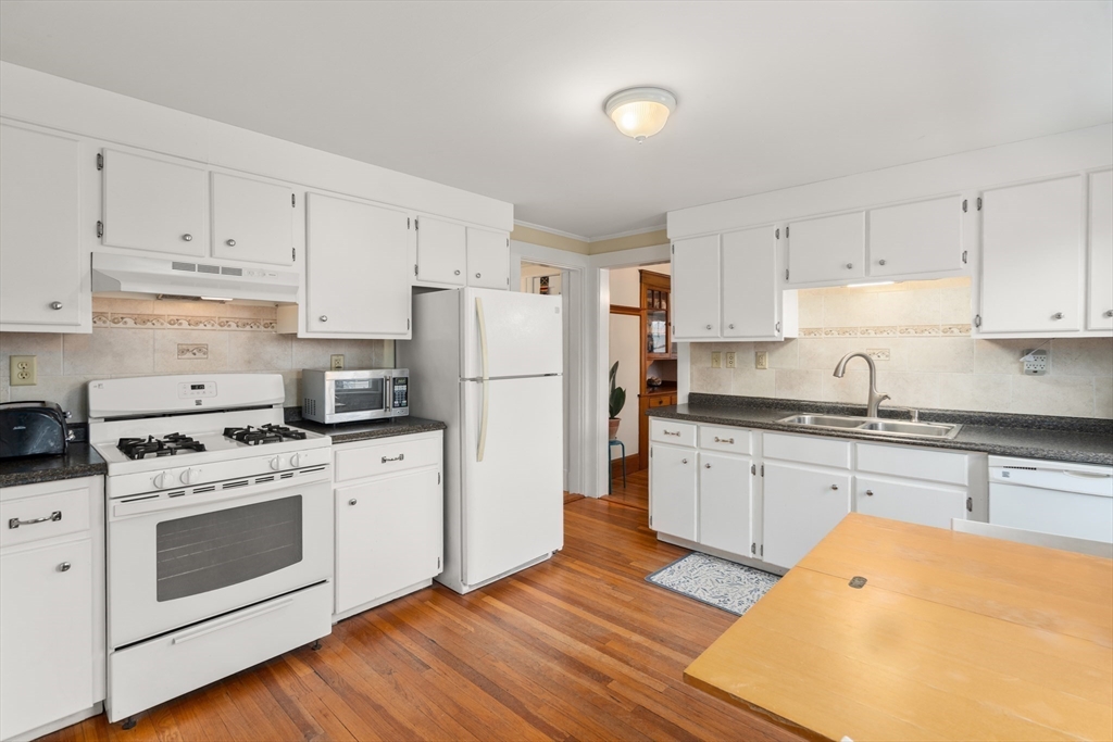 4 Albano Street, Unit 2 Boston, MA 02131 - Photo 12 of 24 a kitchen with stainless steel appliances granite countertop a refrigerator stove a sink dishwasher and white cabinets with wooden floor