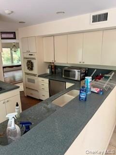 1117 Cedar Ridge Road Oyster Bay, NY 11771 - Photo 9 of 41 a kitchen with stainless steel appliances granite countertop a sink dishwasher stove and white cabinets with wooden floor
