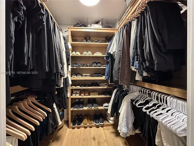 a view of walk in closet with clothes and shoes