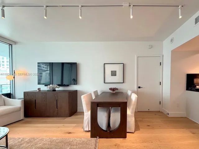 a living room with furniture a flat screen tv and a refrigerator