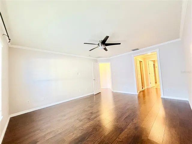 a view of empty room with wooden floor and fan