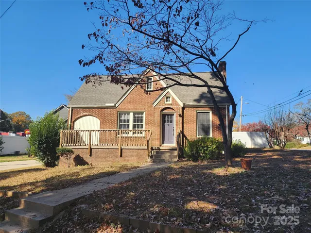 a view of a white house with a big yard and large tree