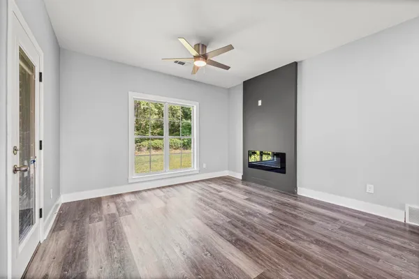 a view of empty room with wooden floor and fan