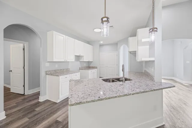 a kitchen with kitchen island granite countertop a sink cabinets and wooden floor
